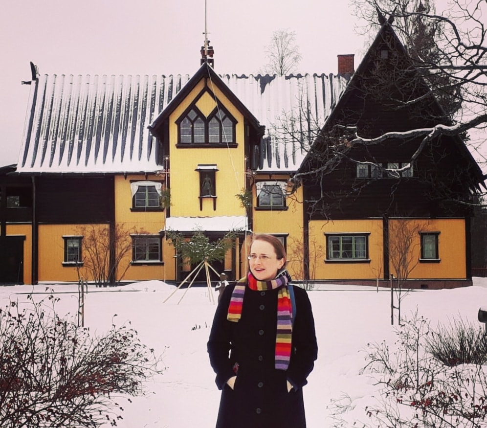 The author Anca Rusu outside a yellow house with snow in Mora