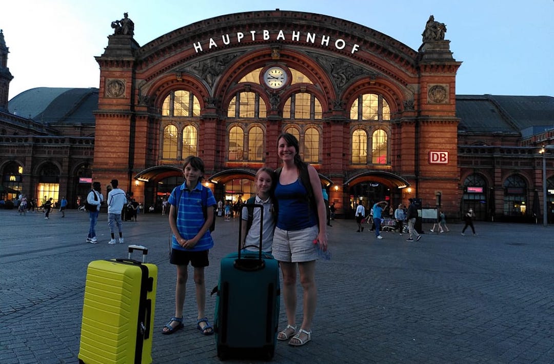 Three people standing in front of Bremen Hauptbahnhof station with their suitcases