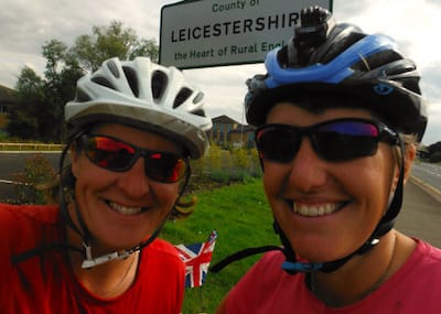 Debs and Jo on their bikes in front of the Leicestershire county sign
