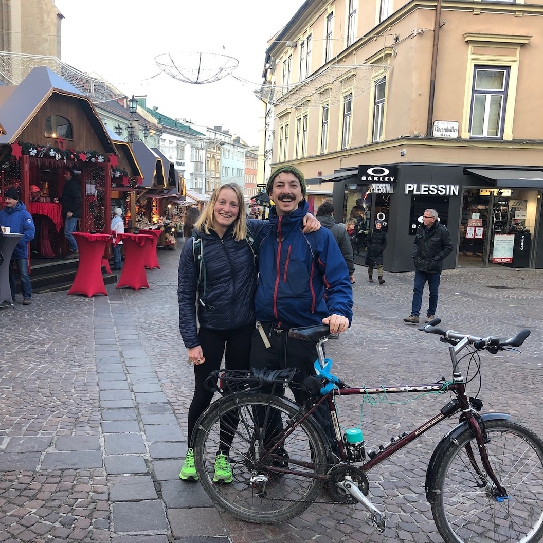 Picture shows Rosie and Mike with their arms around each other, smiling. They are in a city centre and mike is holding his bike.
