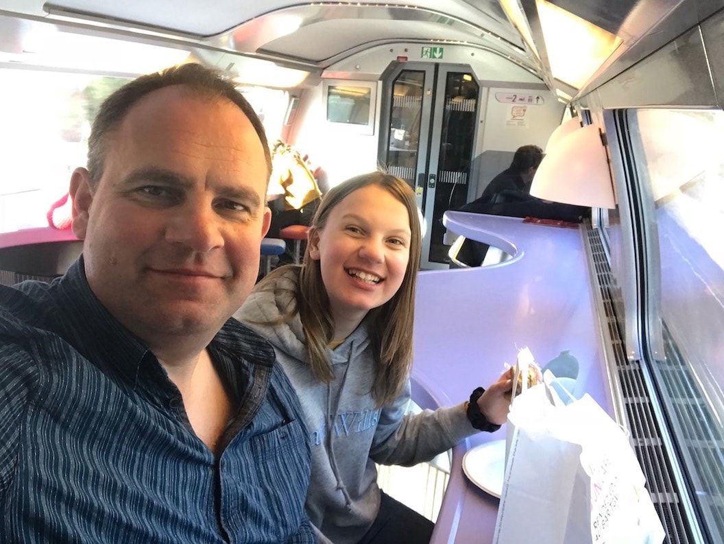  Picture shows Tom and his daughter taking a smiling selfie inside the cafe carriage of their train. 