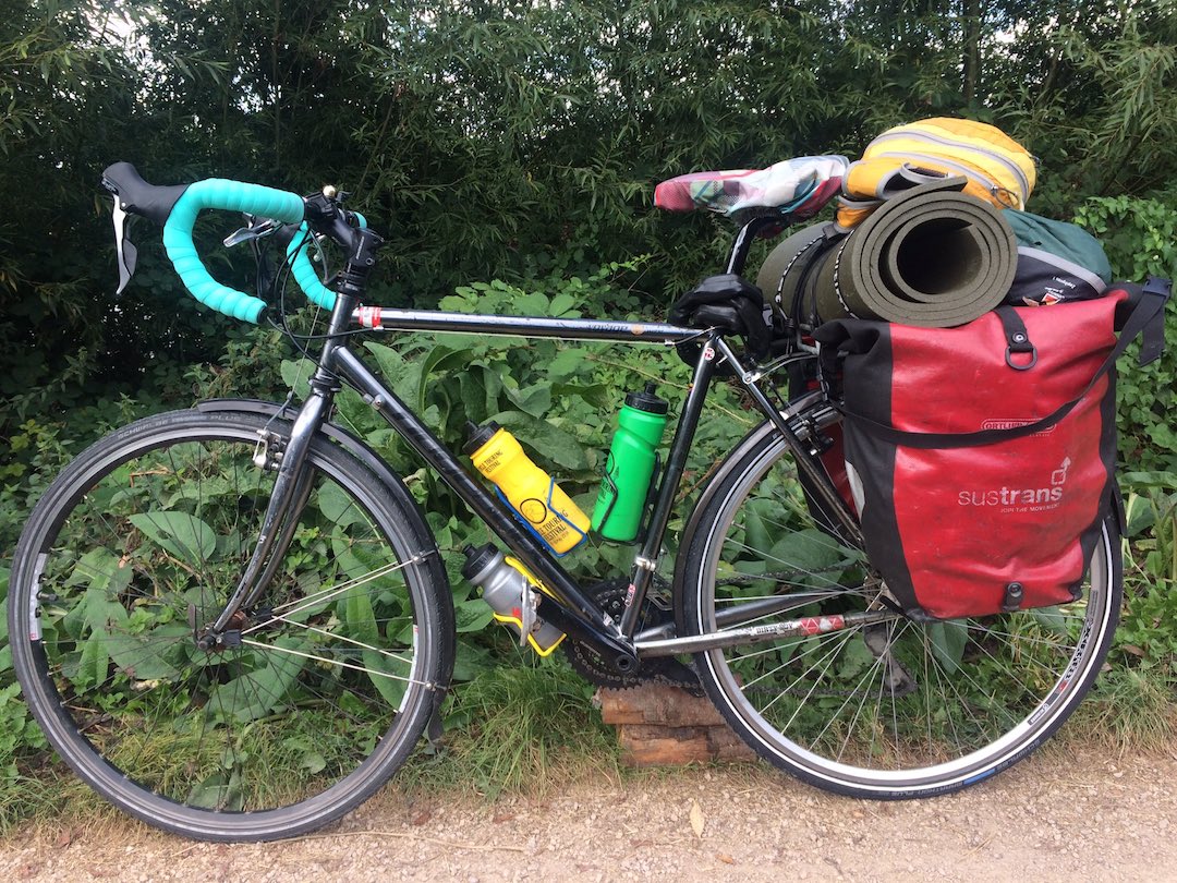 A touring bicycle loaded with panniers, tent and roll mat